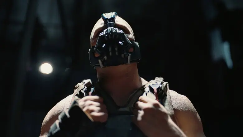 Bane fills the frame in a hard, low-angle portrait in The Dark Knight Rises