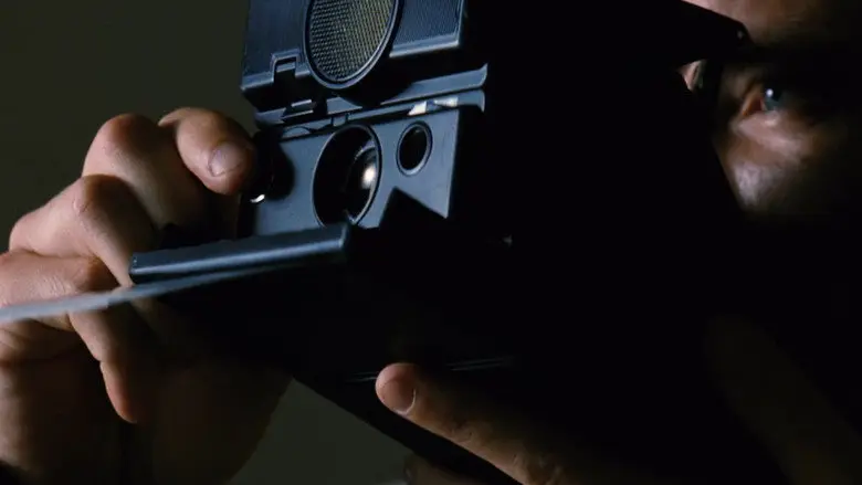 Leonard holding a Polaroid camera in Memento