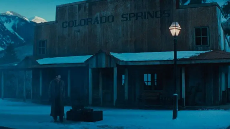 A man with luggage outside a Colorado Springs building in The Prestige