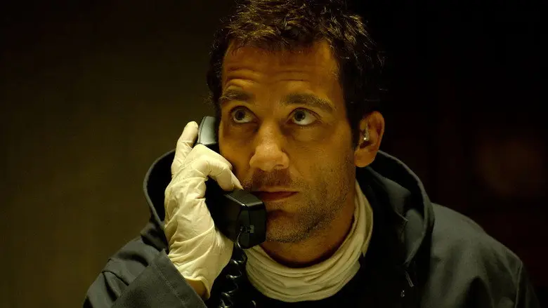 A masked man in sunglasses speaking on a phone in a dim room in Inside Man