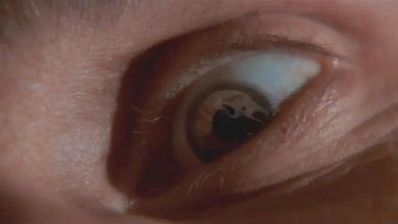 A close view of a frightened eye reflecting the shape of a knife
