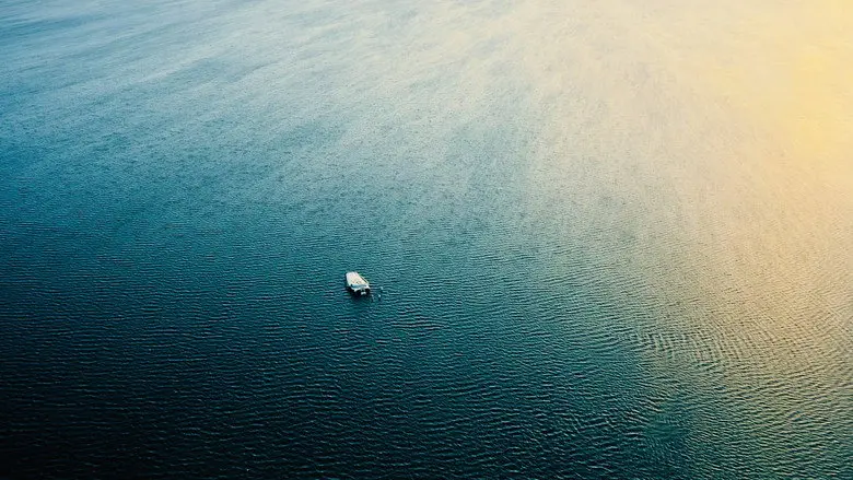 A small white vehicle on dark blue water under pale light in Interstellar