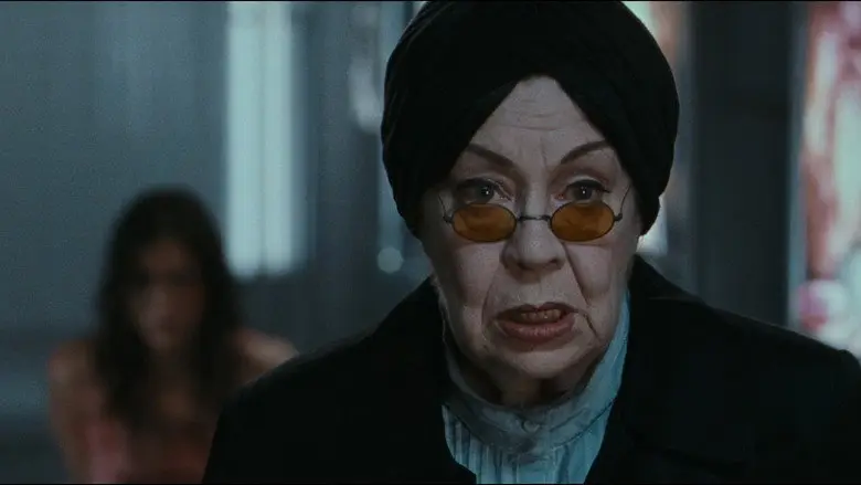 An older woman in dark clothing and tinted glasses in Martyrs